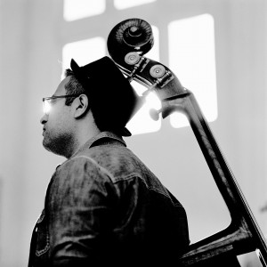 Adam Ben Ezra's head with his double bass in front of a window.