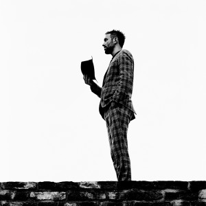 Charlie Winston holding his hat in hand wearing suit.