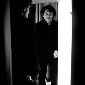 Emir Kusturica posing with his reflection in the mirror in changing room in the boutique.