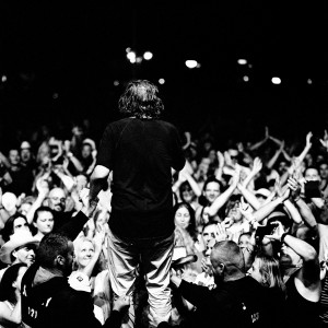 Emir Kusturica standing back on the stage at the concert of No Smoking Orchestra with the audience.