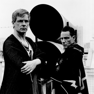 Gus Gus members Daniel Agust Haraldsson and Birgir Porarinsson posing at two tubes on a rooftop of a building.