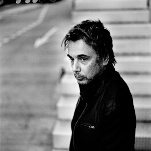 Jean-Michel Jarre standing at a stairway wearing black.