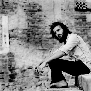 Jean Rondeau sitting on the stairs with old brick wall in the background.