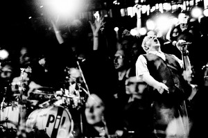 Double exposure of John Lydon Pil on the stage at his concert and faces in the audience.