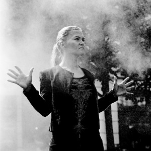 Mari Samuelsen making gesture with her palms in the steam with trees in the background.