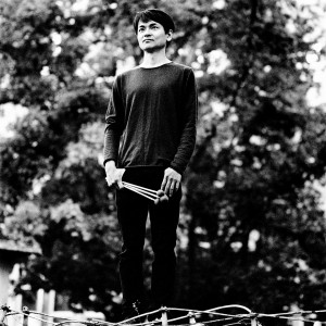 Masayoshi Fujita standing holding the sticks in front of trees.